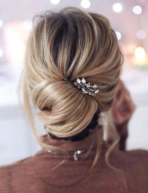 a messy low chignon hairstyle with bangs and a rhinestone headpiece