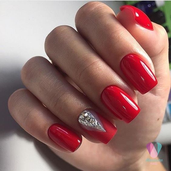 a classic red manicure spruced up for the holidays with a rhinestone accent