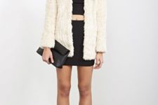 With black crop top, mini skirt, ankle boots and clutch