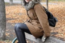 With leather pants, white beanie, brown parka coat and black backpack