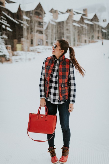 With plaid shirt, jeans, duck boots and red bag