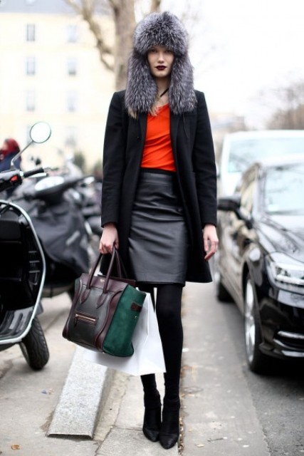 With red shirt, black leather skirt, ankle boots, black coat and two colored bag