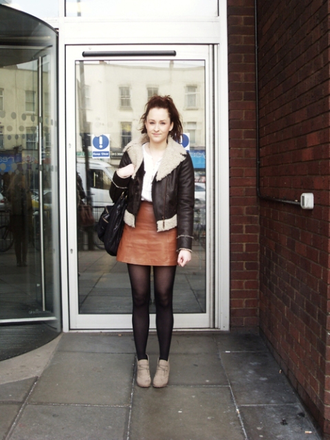 With white shirt, leather skirt, shearling jacket and black bag