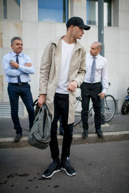 With white t-shirt, black pants, beige trench coat and gray backpack