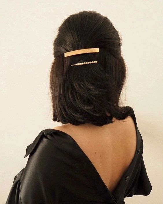 a classic half updo with a sleek top, a gold and pearl hair barrette and hair down is a super chic idea
