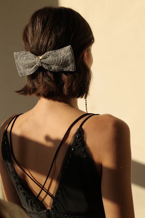 a classic half updo with some volume and texture plus a huge embellished bow as a trendy and bold accent