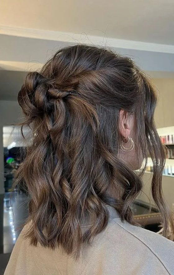 a classy half updo with a halo, a messy top knot and waves down plus locks framing the face