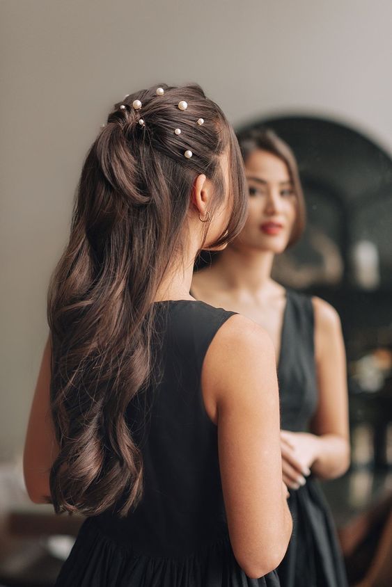 a gorgeous long half updo witha  ponytail, pearls on top and wavy hair down is a stylish and catchy idea