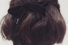 a half updo with twisted touches, a lot of volume and waves, a black velvet ribbon bow is a cool idea
