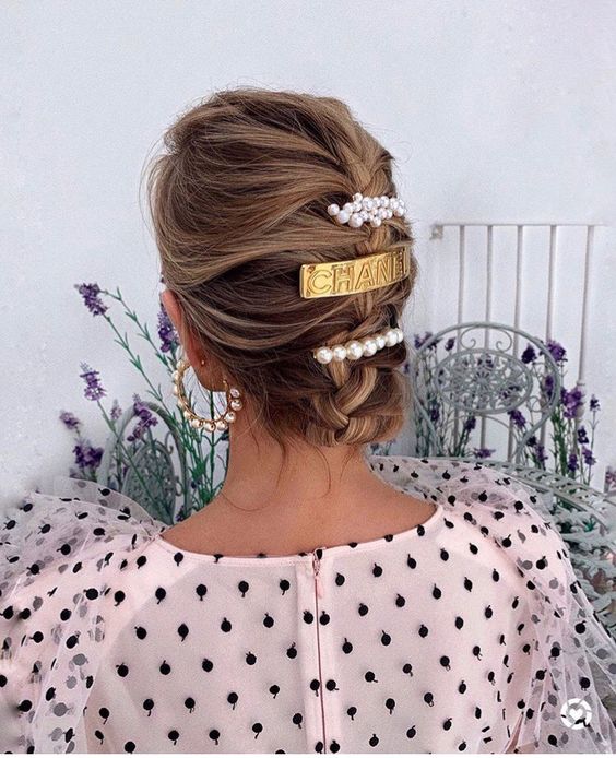 a long bob styled as a braided updo, with pearl hair barrettes and a gold one for a romantic party look