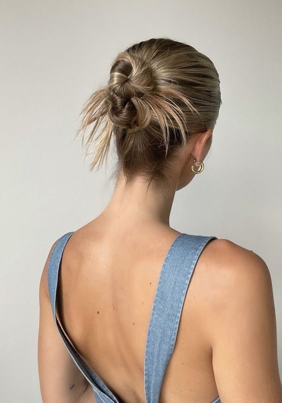 a messy double top knot with a sleek top and some hair is a cool and catchy solution for those who have medium to long hair