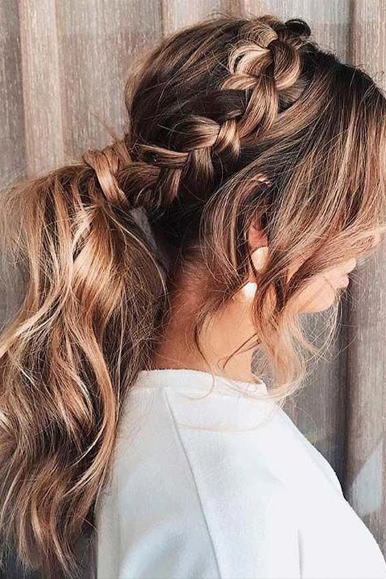 a messy low wavy ponytail with a braided halo, a bump and face-framing locks is a cool idea for many occasions
