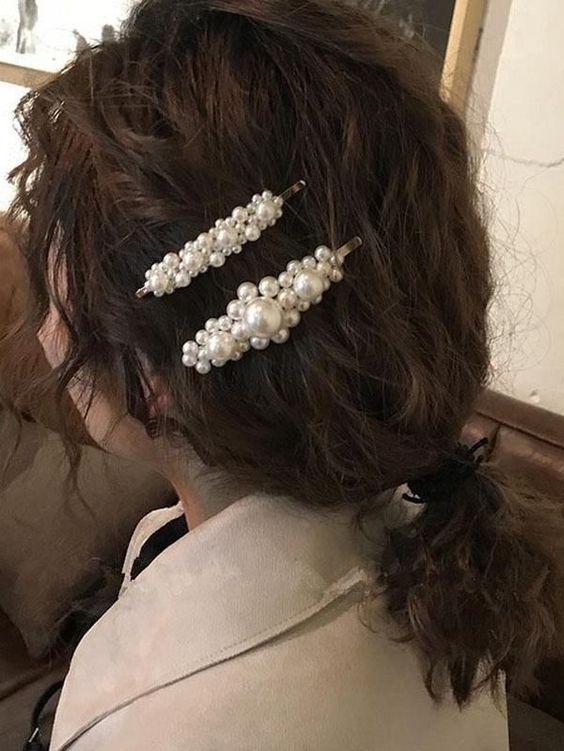 a messy wavy ponytail with pearl hair pins is a cool and catchy hairstyle to rock