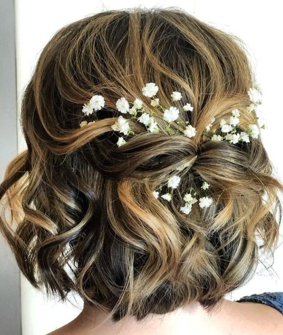 a pretty twisted half updo with waves and baby's breath tucked in is a great idea for a boho or rustic look