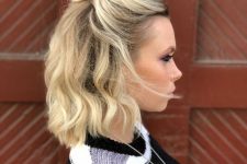 a quick and simple half updo with a messy top knot and waves down plus a lot of volume is chic and catchy
