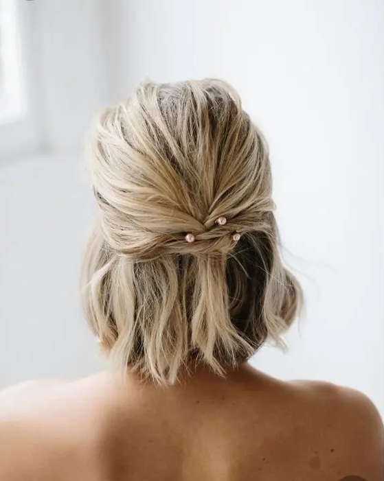 short textural and wavy hair done into a half updo with blush pearl hairpins is a lovely idea thta won’t take much effort