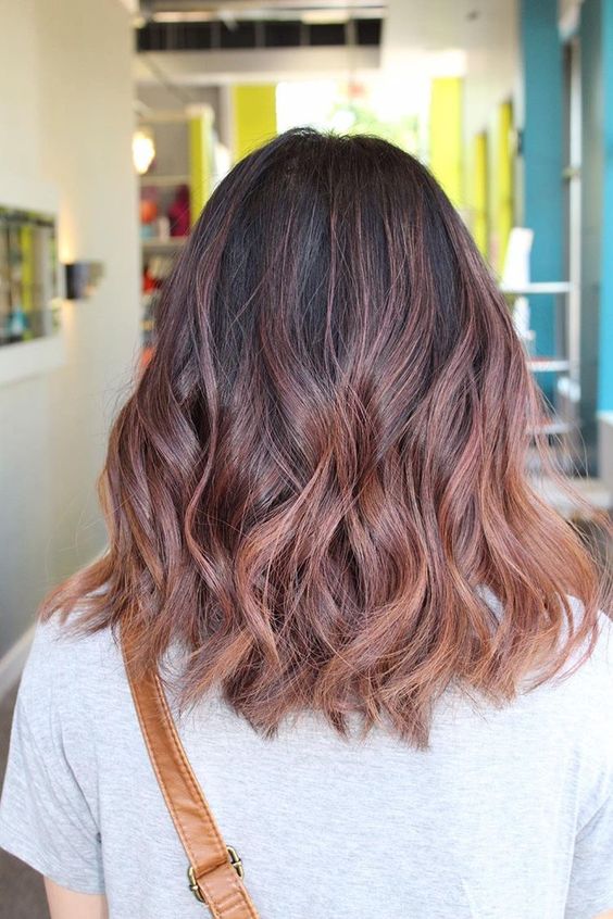 a black base with rose gold balayage with subtle waves looks very chic