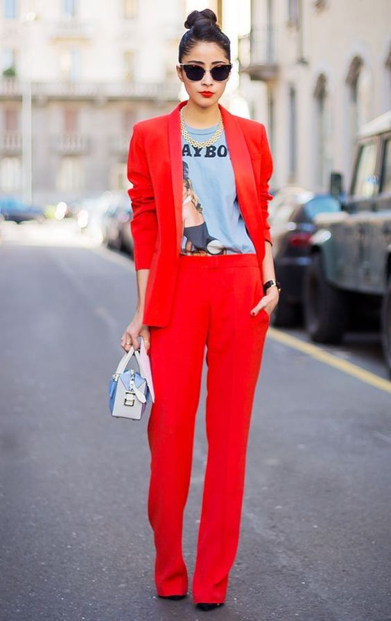 a red pantsuit, a printed shirt, a statement necklace and a small bag
