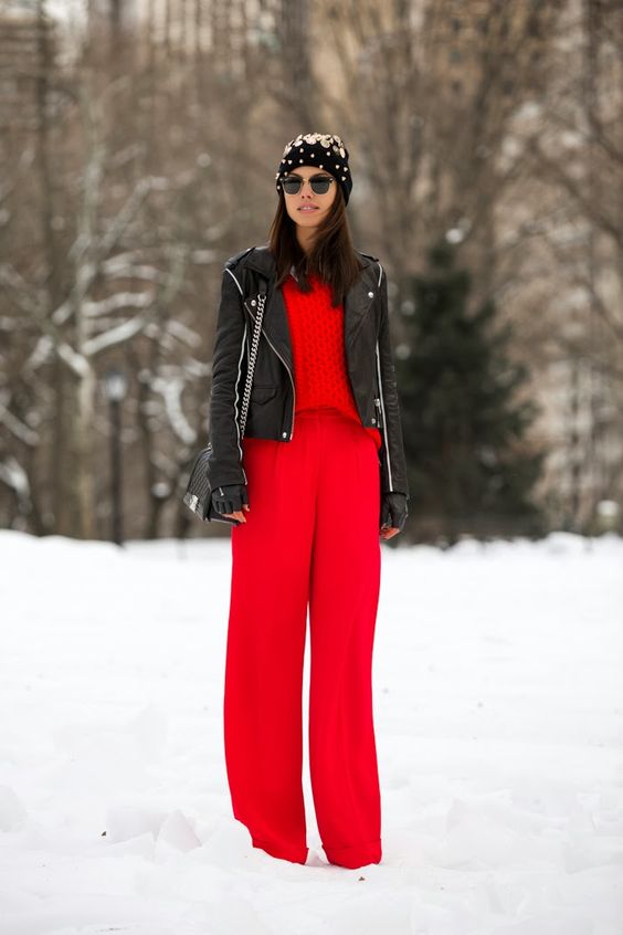 red wide pants, a red sweater, a black leather jacket and an embellished beanie