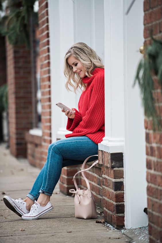 a red chunky knit sweater, blue skinnies, white sneakers and a blush bag