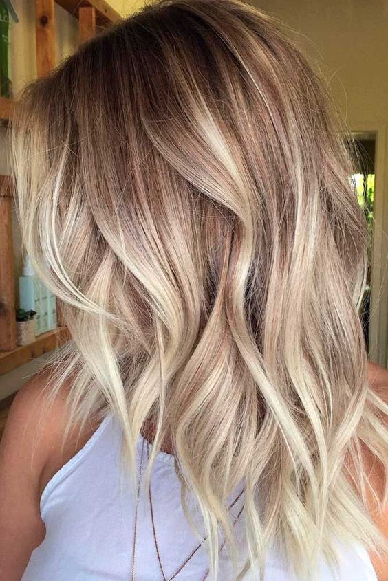 blonde balayage on wavy layered chestnut hair is a cute and girlish idea