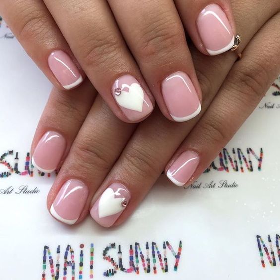 French manicure with white nail hearts topped with rhinestones for a stylish look