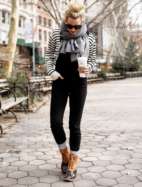 a striped top, a black overall, snow boots and a comfy cashmere scarf