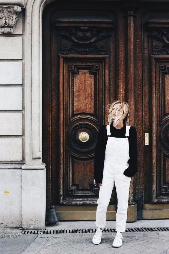 an oversized black sweater, a white overall and sneakers for a comfy and warm look