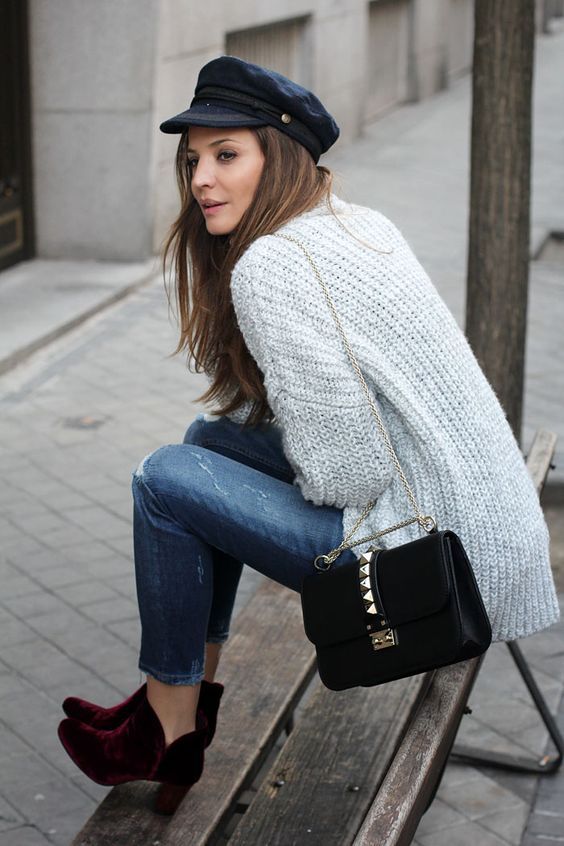 cropped ripped denim, plum-colored velvet booties, a grey chunky knit sweater and a black cap