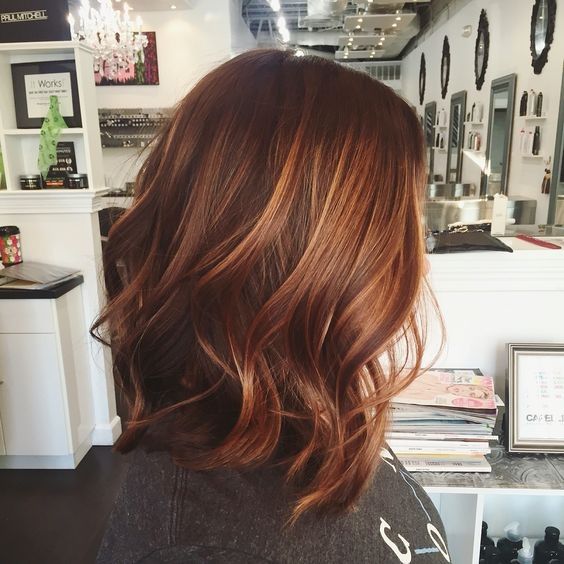 red wavy hair with lighter fiery orange balayage that makes the look bolder