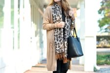 With beanie, beige cardigan, skinny pants, brown ankle boots and black tote