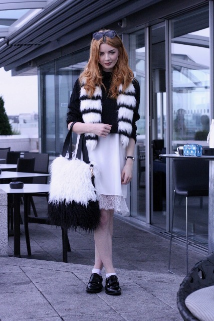 With black shirt, white skirt, flat boots and fur bag