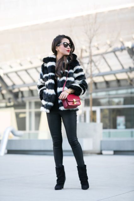 With black skinny pants, mid calf boots and red bag