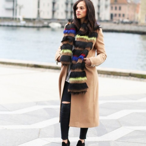 With camel coat, distressed pants and ankle boots