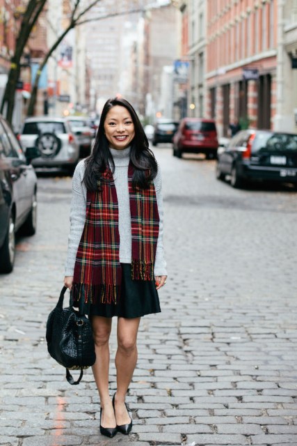 With gray turtleneck sweater, mini skirt, flats and black bag