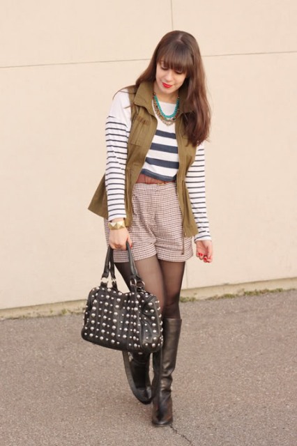 With striped shirt, high boots, olive green vest and black bag