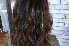 a black medium-length wavy hairstyle with caramel highlights and waves is a timeless idea to rock