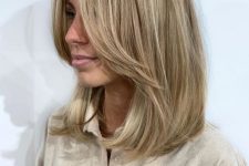 a medium-length blonde hairstyle with long curtain bangs and blonde balayage is a lovely and chic idea