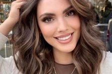a medium-length chocolate brown hairstyle with cold brew highlights, waves and volume is a lovely idea to try