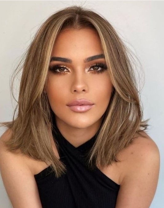 a soft bronde outgrown bob with a bit of blonde highlights and soft curtain bangs dyed blonde, too