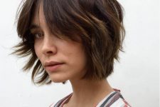 a textured brown chin-length bob with a bit of caramel balayage and a lot of texture looks cool