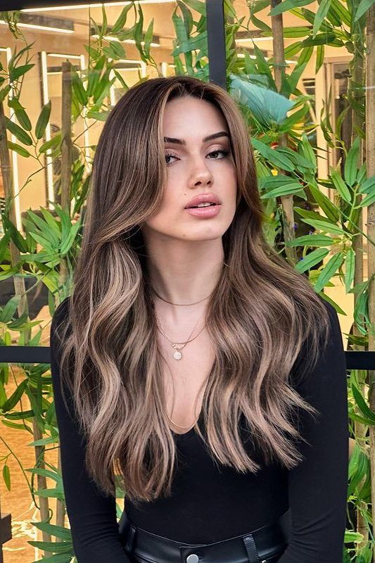 dark brown hair with bronde highlights and waves plus long curtain bangs looks chic, fresh and bright