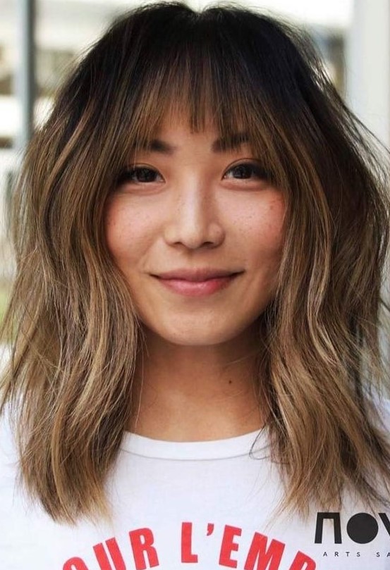 dark brunette medium-length hair with caramel balayage and ombre, wispy bangs and slight messy waves is a cool idea