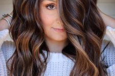 dark chestnut brown hair with waves and with delicate and subtle caramel balayage that highlights the chestnut shade and makes it bolder