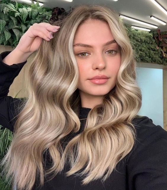Gorgeous long hair with blonde balayage and waves looks amazing, and face framing locks accent the face features