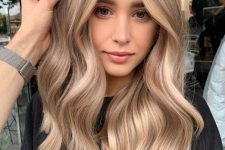 long and beautiful hair with blonde balayage and waves looks very elegant, chic and shiny and face-framing highlights accent the face features