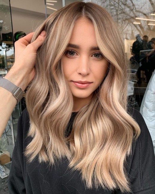Long and beautiful hair with blonde balayage and waves looks very elegant, chic and shiny and face framing highlights accent the face features