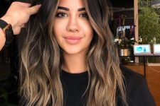 long dark brunette hair with bronde balayage and face-framing highlights and waves looks very eye-catching
