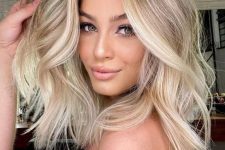 medium-length blonde hair with a shadow root and brighter balayage plus waves and volume is chic