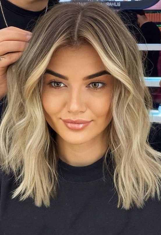 medium-length blonde hair with a shadow root and slight waves is a cool idea, it looks stylish and chic